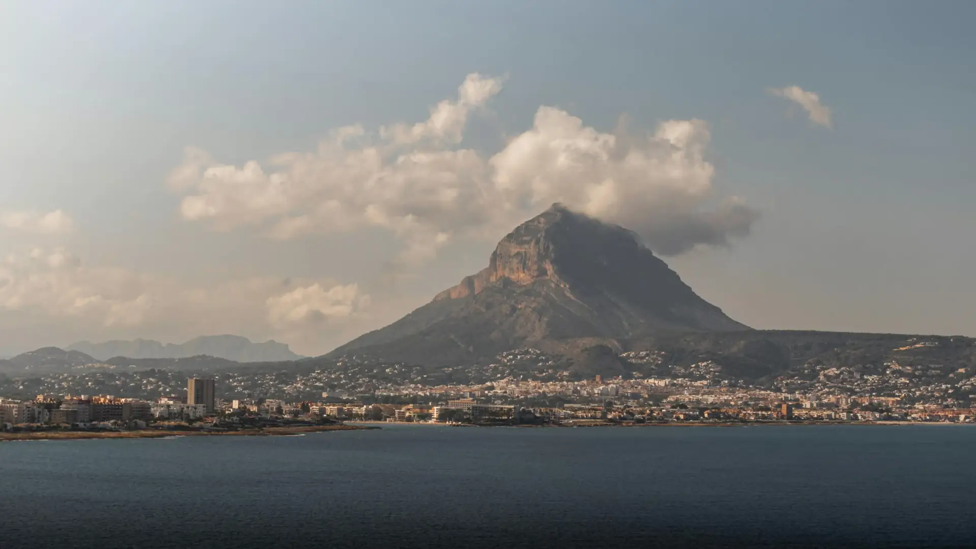 Aerial view of Javea's coastline with the majestic Montgó Mountain overlooking the town and the Mediterranean Sea.