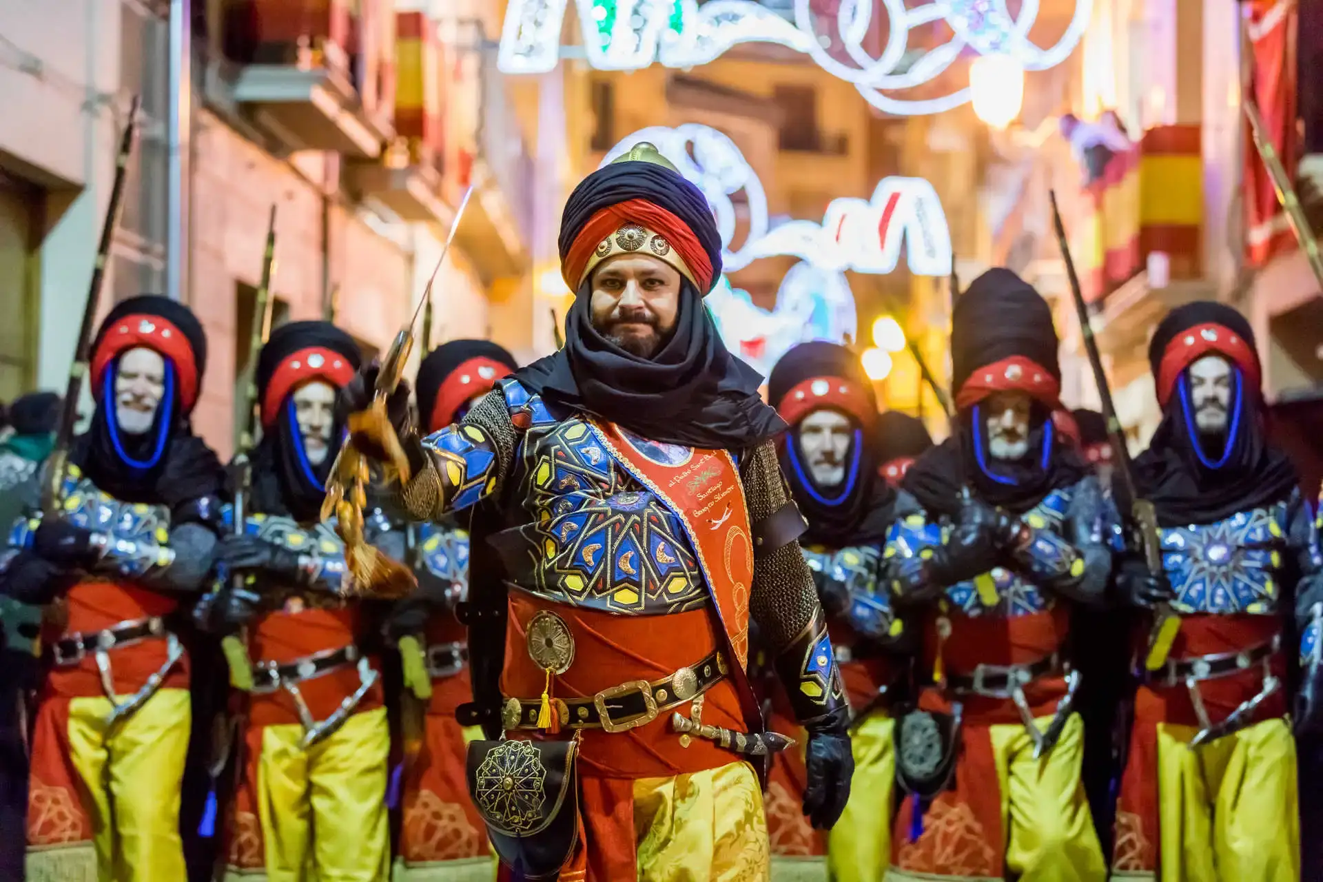 Participants in elaborate historical costumes marching in the vibrant Moors and Christians Festival parade in Javea, Spain.
