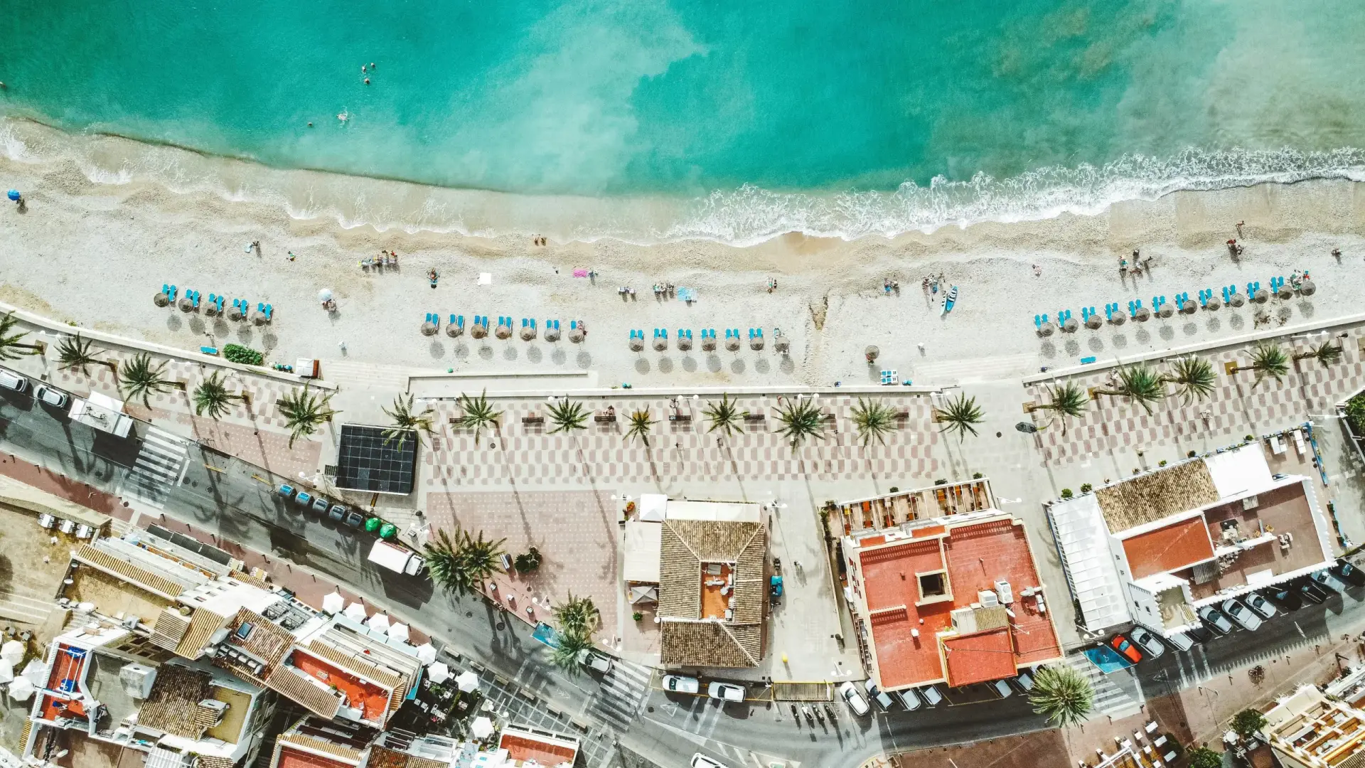 Aerial view of a Spanish beach and coastal town, illustrating desirable real estate in Spain relevant to property tax discussions.