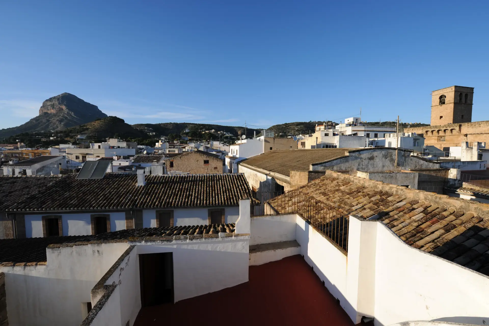 Rooftop view of Javea Old Town with San Bartolomé Church and Montgó mountain, highlighting local charm.