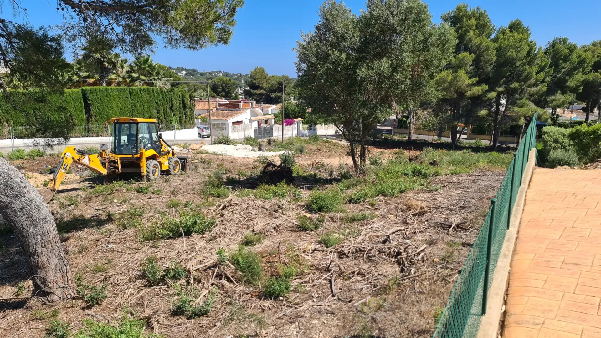 Construction site of a ready-to-build luxury villa plot in Carrer del Roget, Javea, with an excavator on site.